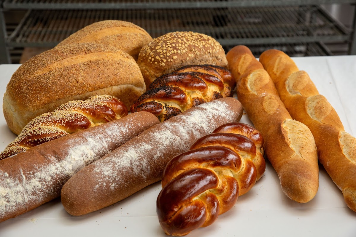 An assortment of fresh-baked Wheatland Bakery breads: challah, baguettes, and sourdough loaves